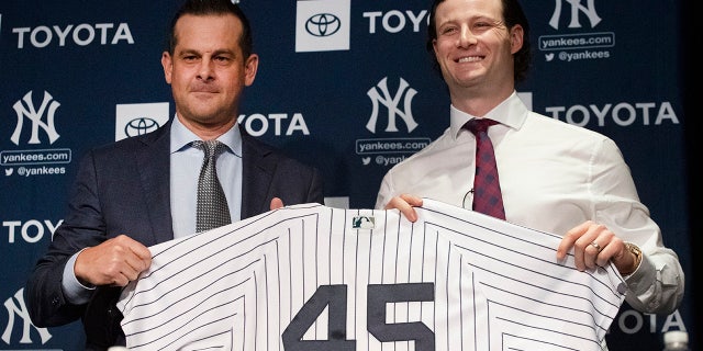 New York Yankees manager Aaron Boone, left, and pitcher Gerrit Cole hold up a jersey as Cole is introduced as the baseball club's newest player during a media availability, Wednesday, Dec. 18, 2019 in New York. The pitcher agreed to a 9-year, $324 million contract. (AP Photo/Mark Lennihan)