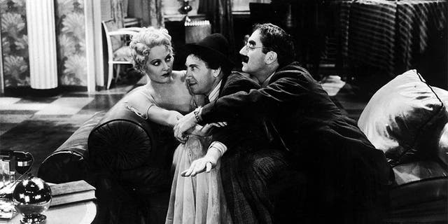 American comedian Groucho Marx (1890 - 1977, right) and his brother Chico (1887 - 1961) pay homage to the college widow, played by Thelma Todd (1906 - 1935), in a scene from "Horse Feathers," directed by Norman Z. McLeod, 1932.