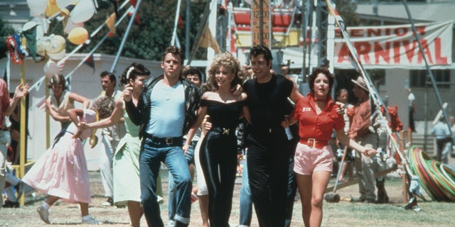 1978: Left to right: actors Jeff Conaway, Olivia Newton-John, John Travolta and Stockard Channing walk arm in arm at a carnival in a still from the film, 'Grease' directed by Randal Kleiser. 