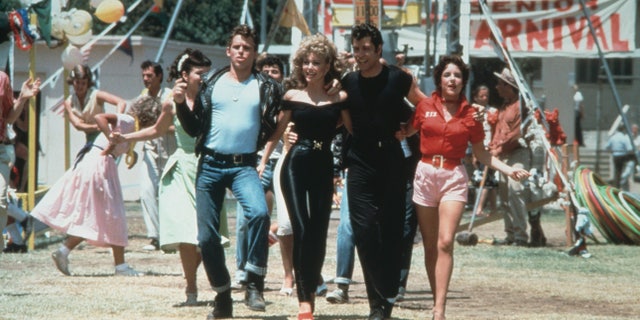 1978: Left to right: actors Jeff Conaway, Olivia Newton-John, John Travolta and Stockard Channing walk arm in arm at a carnival in a still from the film, 'Grease' directed by Randal Kleiser. 