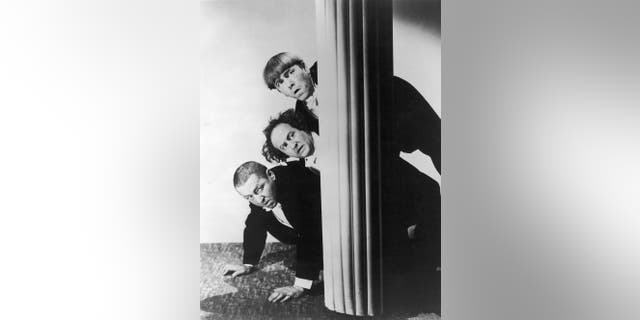 Circa 1940: The Three Stooges peer around a column while hiding. Top to bottom: Moe Howard (1897 - 1975), Larry Fine (1902 - 1975) and Curly Howard (1903 - 1952).