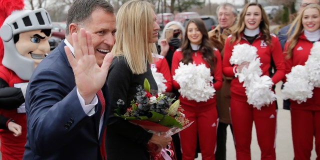 New Rutgers NCAA college football coach Greg Schiano greets supporters as he arrives for a news conference in Piscataway, N.J., with his wife, Christy, Wednesday, Dec. 4, 2019. After an on-again, off-again courtship, Schiano is back as Rutgers football coach. (AP Photo/Seth Wenig)