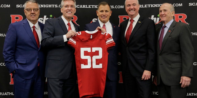 New Rutgers NCAA college football head coach Greg Schiano, center, poses for a picture with Greg Brown, chairman of the Committee on Intercollegiate Athletics, left, Rutgers athletic director Pat Hobbs, second from left, New Jersey Gov. Phil Murphy, second from right, and Rutgers president Robert Barchi, right, after an introductory news conference in Piscataway, N.J., Wednesday, Dec. 4, 2019. After an on-again, off-again courtship, Schiano is back as Rutgers football coach. (AP Photo/Seth Wenig)