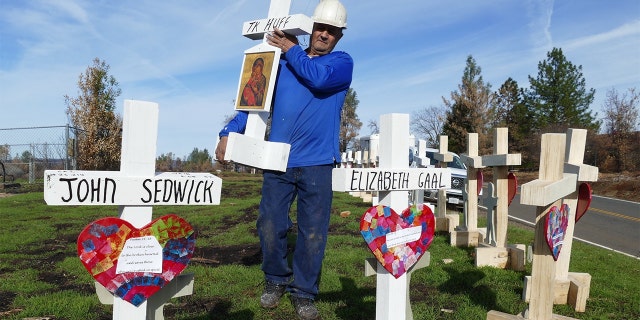 Carpenter Greg Zanis sets up wooden crosses in memory of the dead of the "Camp" fire in the Paradise area at the entrance to the village along the main access road. Zanis made wooden crosses in memory of deaths from mass shootings and other incidents. Photo: Barbara Munker/dpa (Photo by Barbara Munker/picture alliance via Getty Images)