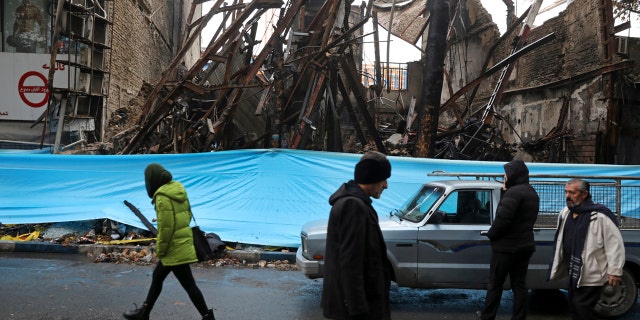 In this Nov. 20, 2019, file photo, people walk past buildings that were burned during recent protests, in Shahriar, Iran, some 25 miles southwest of the capital, Tehran.
