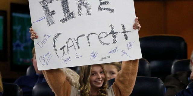 A young fan holds a sign calling for the firing of Dallas Cowboys head coach Jason Garrett in the second half of an NFL football game against the Buffalo Bills in Arlington, Texas, Thursday, Nov. 28, 2019. (AP Photo/Ron Jenkins)