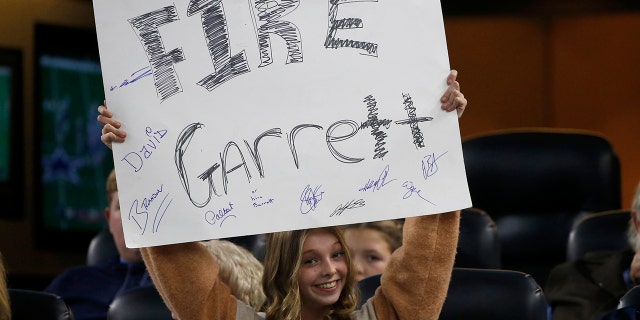 A young fan holds a sign calling for the firing of Dallas Cowboys head coach Jason Garrett in the second half of an NFL football game against the Buffalo Bills in Arlington, Texas, Thursday, Nov. 28, 2019. (AP Photo/Ron Jenkins)