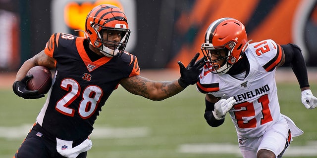 Cincinnati Bengals running back Joe Mixon (28) rushes against Cleveland Browns cornerback Denzel Ward (21) during the first half of an NFL football game, Sunday, Dec. 29, 2019, in Cincinnati. (AP Photo/Bryan Woolston)