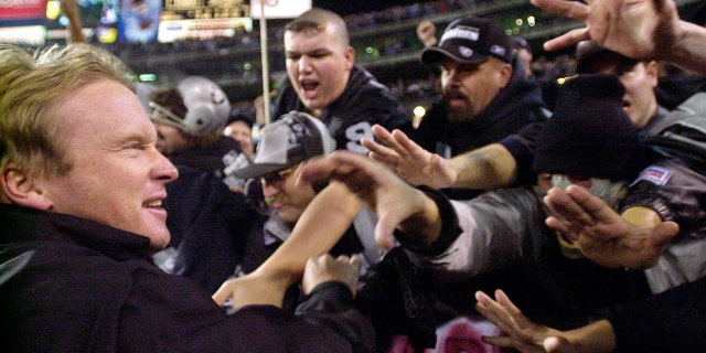 FILE - In this Jan. 12, 2002, file photo, Oakland Raiders head coach Jon Gruden greets fans in the "Black Hole" after the Raiders beat the New York Jets 38-24 during the AFC Wildcard playoff NFL football game in Oakland, Calif. The Raiders' final scheduled game in Oakland on Sunday, Dec. 15, 2019, will be an emotional one for players and coaches, as well as fans. (AP Photo/Paul Sakuma, File)