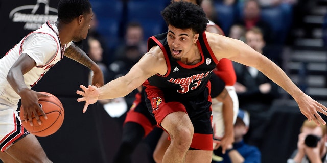 Louisville forward Jordan Nwora (33) reaches for the ball as he tries to knock it away from Western Kentucky guard Taveion Hollingsworth (11) during the second half of an NCAA college basketball game Friday, Nov. 29, 2019, in Nashville, Tenn. (AP Photo/Mark Zaleski)