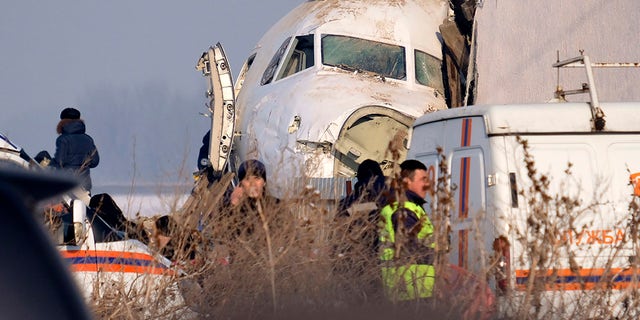 Police stand guard as rescuers assist on the site of a plane crashed near Almaty International Airport, outside Almaty, Kazakhstan, Friday, Dec. 27, 2019. The Kazakhstan plane with 98 people aboard crashed shortly after takeoff early Friday. 