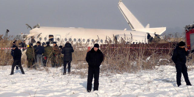 Police stand guard as rescuers assist on the site of a plane crash near Almaty International Airport, outside Almaty, Kazakhstan, Friday, Dec. 27, 2019. Almaty International Airport said the Bek Air plane crashed Friday in Kazakhstan shortly after takeoff causing numerous deaths. The aircraft had 100 passengers and crew onboard when hit a concrete fence and a two-story building shortly after takeoff. 