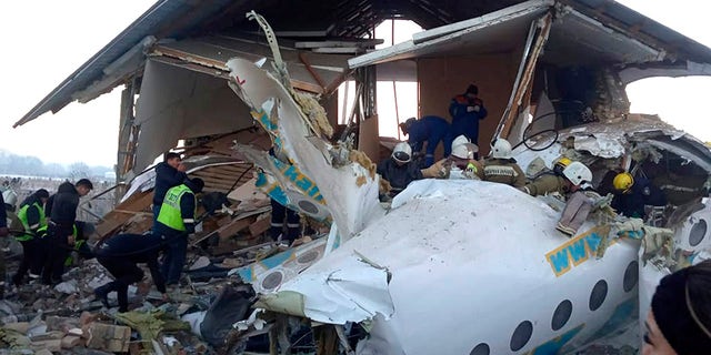 In this handout photo provided by the Emergency Situations Ministry of the Republic of Kazakhstan, police and rescuers work on the side of a plane crash near Almaty International Airport, outside Almaty, Kazakhstan, Friday, Dec. 27, 2019. Almaty International Airport said a Bek Air plane crashed Friday in Kazakhstan shortly after takeoff causing numerous deaths. The aircraft had 100 passengers and crew onboard when hit a concrete fence and a two-story building shortly after takeoff.