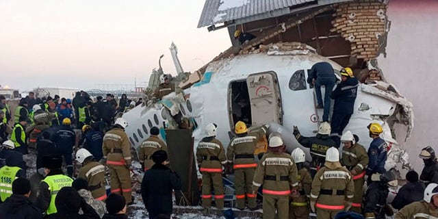 In this handout photo provided by the Emergency Situations Ministry of the Republic of Kazakhstan, police and rescuers work on the site of a plane crash near Almaty International Airport, outside Almaty, Kazakhstan, Friday, Dec. 27, 2019. Almaty International Airport said a Bek Air plane crashed Friday in Kazakhstan shortly after takeoff causing numerous deaths. The aircraft had 100 passengers and crew onboard when hit a concrete fence and a two-story building shortly after takeoff.