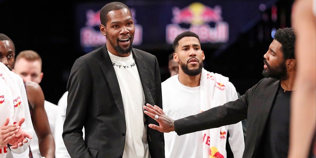 Injured Brooklyn Nets guard Kyrie Irving, right, puts his hand on fellow injured player Kevin Durant who smiles as he stands to greet teammates returning to the bench during a timeout in the second half of an NBA basketball game against the New York Knicks, Thursday, Dec. 26, 2019, in New York. (AP Photo/Kathy Willens)