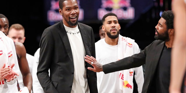 Injured Brooklyn Nets guard Kyrie Irving, right, puts his hand on fellow injured player Kevin Durant who smiles as he stands to greet teammates returning to the bench during a timeout in the second half of an NBA basketball game against the New York Knicks, Thursday, Dec. 26, 2019, in New York. (AP Photo/Kathy Willens)