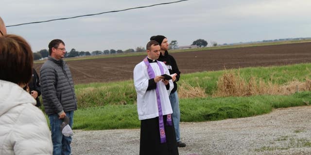 Rev. Matthew Barzare blesses 100 gallons of water on an airstrip.