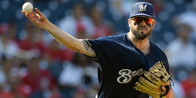 FILE - In this Aug. 18, 2019, file photo, Milwaukee Brewers third baseman Mike Moustakas throws the ball to first during a baseball game against the Washington Nationals in Washington. (AP Photo/Nick Wass, File)