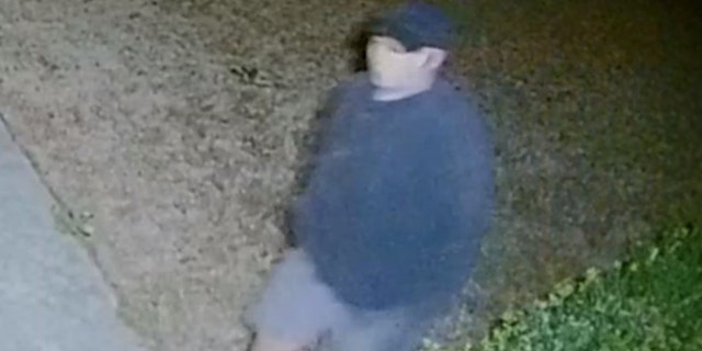 The man appears to wear a baseball cap, a blue sweatshirt or jacket and light blue shorts with white socks and black shoes in most footage.