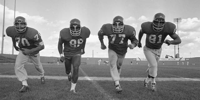 In this Sept. 16, 1971 photo, the powerful defensive front four of the Minnesota Vikings , from left, Jim Marshall, Alan Page, Gary Larson, Carl Eller pose during NFL football practiced in Minneapolis. Helmets have evolved from the original hard leather of the NFL’s infancy to hard polycarbonate single-piece shells with various amounts of padding and air bladders that served as the primary form of head protection into the beginning of this century. (AP Photo/File)