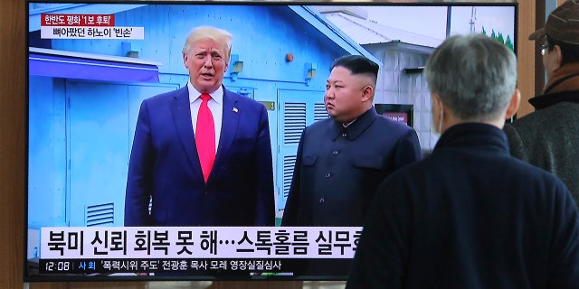 People watch a TV screen showing a file image of North Korean leader Kim Jong Un and U.S. President Donald Trump, left, during a news program at the Seoul Railway Station in Seoul, South Korea, Tuesday, Dec. 31, 2019. The sign reads: