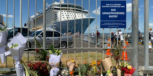 Flowers are laid on makeshift memorial is seen in front of cruise ship Ovation of the Seas, in Tauranga, New Zealand, Tuesday, Dec. 10, 2019.