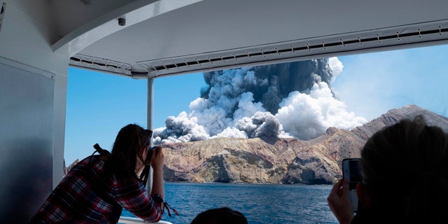 In this Monday, Dec. 9, 2019, photo provided by Michael Schade, tourists on a boat look at the eruption of the volcano on White Island, New Zealand.