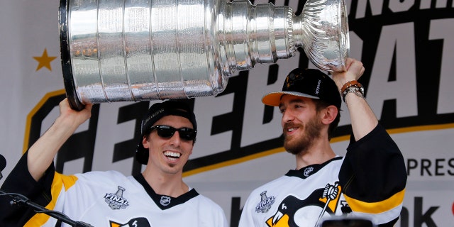 FILE - In this Wednesday, June 14, 2017, file photo, Pittsburgh Penguins goalies Marc-Andre Fleury, left, and Matt Murray hold the Stanley Cup on stage after riding in the Stanley Cup victory parade in Pittsburgh. Managing top goaltenders’ schedules is the NHL’s version of load management. Each of the past five Stanley Cup-winning goalies started fewer than 60 games in the regular season, along with three of the past five runners up. (AP Photo/Gene J. Puskar, File)