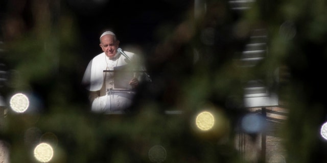 Pope Francis, framed by the St. Peter's Square Christmas tree, reads his message during the Angelus noon prayer he recited from the window of his studio, at the Vatican, Sunday, Dec. 1, 2019. (AP Photo/Alessandra Tarantino)