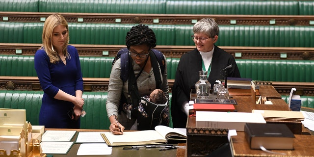 Britain's Conservative MP Kemi Badenoch attends a swearing-in ceremony in London while carrying her child.