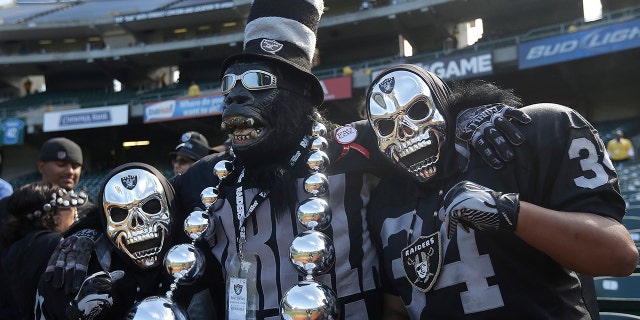 FILE - In this Sept. 29, 2013, file photo, Oakland Raiders fan Gorilla Rilla, center, poses for photographs with fans before an NFL football game between the Oakland Raiders and the Washington Redskins in Oakland, Calif. The Raiders' final scheduled game in Oakland on Sunday, Dec. 15, 2019, will be an emotional one for players and coaches, as well as fans. (AP Photo/Marcio Jose Sanchez, File)