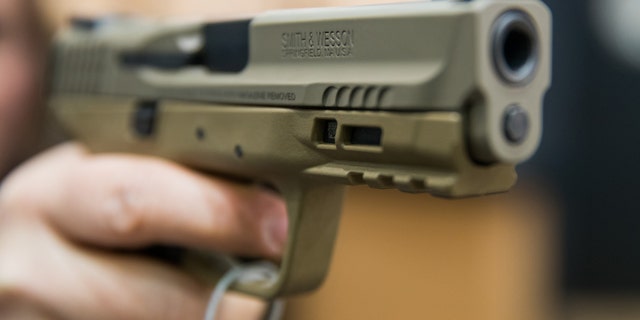 A woman holds a 9-mm. handgun by the American manufacturer Smith & Wesson at the IWA OutdoorClassics trade show for hunting, shooting sports, equipment for outdoor activities and for civilian and official security applications in March 2018 in Nuremberg, Germany.