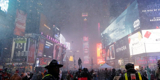 Pedestrians observe a snow squall in Times Square Wednesday, Dec. 18, 2019, in New York.