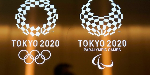 FILE - In this June 11, 2019, file photo, a man walks past the logos of the Tokyo 2020 Paralympics and Olympics in Tokyo. Ticket demand for the Tokyo Paralympics is at record levels. The unprecedented demand follows a similar surge in interest for the Tokyo Olympics. The president of the International Paralympic Committee said Tuesday, Dec. 10, 2019, there were 3.1 million tickets requests in the first lottery phase earlier this year. (AP Photo/Jae C. Hong, File)