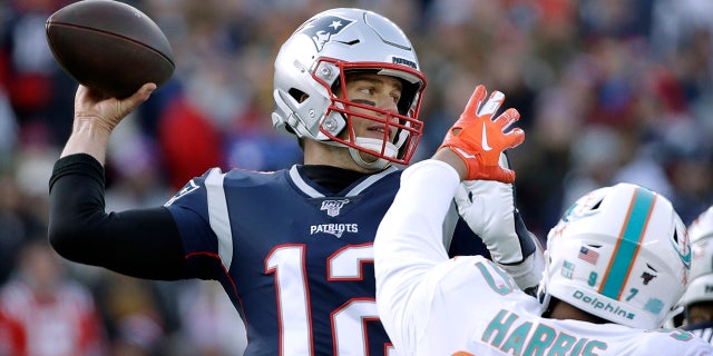 New England Patriots quarterback Tom Brady, left, passing under pressure from Miami Dolphins defensive end Trent Harris Sunday in Foxborough, Mass. (AP Photo/Elise Amendola)