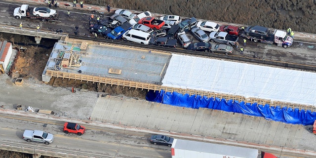 Crews worked to clear vehicles from the Queens Creek overpass on I-64 in York County after a chain-reaction crash involving at least 63 cars. (Rob Ostermaier/The Daily Press via AP)