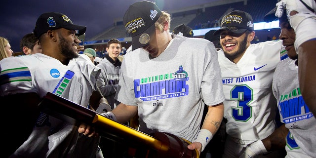 West Florida quarterback Austin Reed, center, holds the trophy while celebrating with teammates after the team won the Division II championship NCAA college football game against Minnesota State, Saturday, Dec. 21, 2019, in McKinney, Texas. (AP Photo/Gareth Patterson)