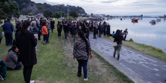 Locals sing during sunrise as they wait for the return of the victims after the White Island eruption to be returned to Whakatane, New Zealand, Friday, Dec. 13, 2019.