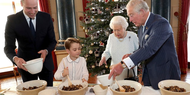 In this photo provided by Buckingham Palace, Britain's Queen Elizabeth, Prince Charles, Prince William and Prince George smile as they prepare special Christmas puddings in the Music Room at Buckingham Palace, London, as part of the launch of The Royal British Legion's Together at Christmas initiative.