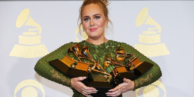 Adele holdomg the five Grammys she won including Record of the Year for "Hello" and Album of the Year for "25" in 2017.