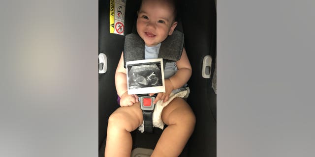 Baby Valentina holding a scan of Santi in the womb.
