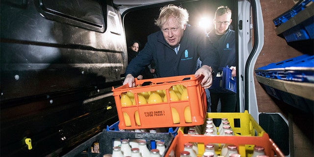 Britain's Prime Minister Boris Johnson loads a crate into a milk delivery van.