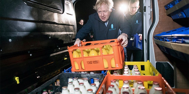 Britain's Prime Minister Boris Johnson loads a crate into a milk delivery van.