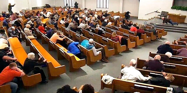 In this still frame from livestreamed video provided by law enforcement, churchgoers take cover while a congregant armed with a handgun, top left, engages a man who opened fire, near top center just right of windows, during a service at West Freeway Church of Christ, Sunday, Dec. 29, 2019, in White Settlement, Texas. (West Freeway Church of Christ/Courtesy of Law Enforcement via AP)