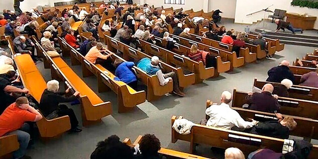 In this still frame from livestreamed video provided by law enforcement, churchgoers take cover while a congregant armed with a handgun, top left, engages a man who opened fire, near top center just right of windows, during a service at West Freeway Church of Christ, Sunday, Dec. 29, 2019, in White Settlement, Texas. (West Freeway Church of Christ/Courtesy of Law Enforcement via AP)