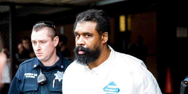 Ramapo police officers escort Grafton Thomas from Ramapo Town Hall to a police vehicle on Sunday in Ramapo, N.Y.
