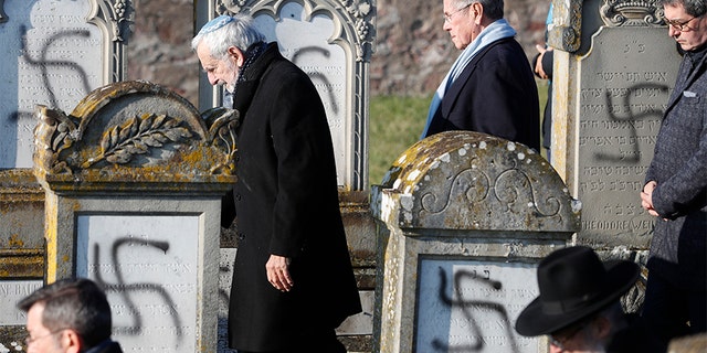 Members of the Jewish community walk amid vandalized tombs in the Jewish cemetery of Westhoffen, west of the city of Strasbourg, on Wednesday. (AP)