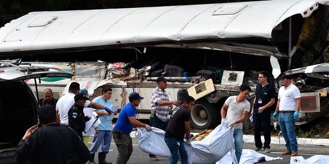 Rescue workers carry body bags with the remains of passengers after a deadly bus accident in Gualan, Guatemala, Saturday, Dec. 21, 2019. The accident killed at least 21 people and left a dozen wounded, according to the national disaster agency. (Associated Press)
