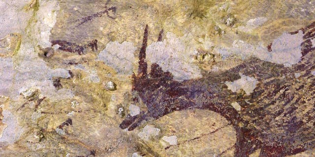This part of a newly described ancient hunting scene includes a miniature buffalo, or anoa (right), facing five faint human-animal figures wielding spears or ropes, a study finds.