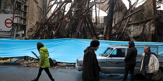 People walk past buildings that were burned during recent protests, in Shahriar, Iran, on Nov. 20.